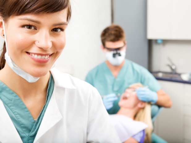 Dental team member smiling as dentist treats dental patient