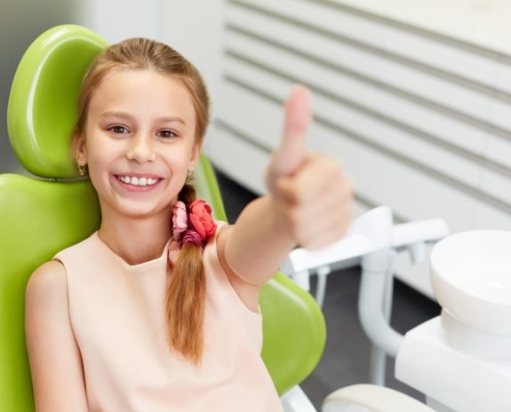 Young person giving thumbs up after dental checkup and teeth cleaning