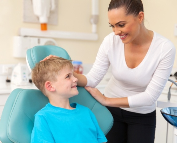 Child smiling at dentist after fitting for athletic mouthguards