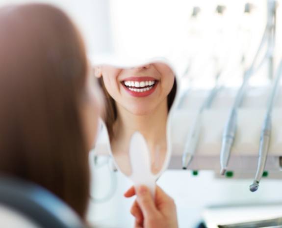 Patient looking at smile in mirror after cosmetic dental bonding