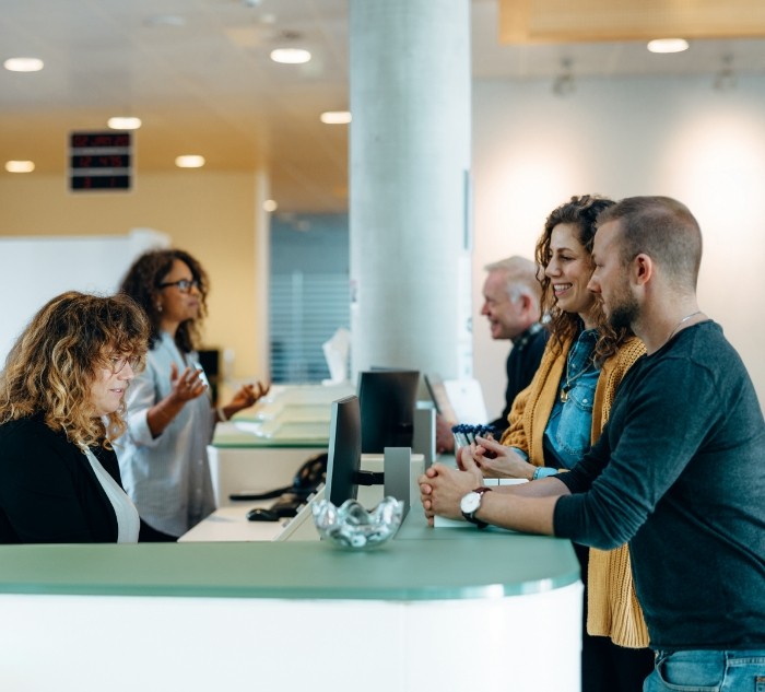 Team members helping patients at reception desk