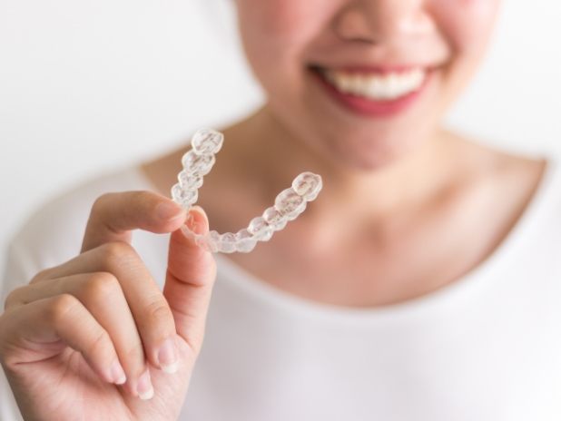 Dental patient holding clear braces orthodontics aligner tray