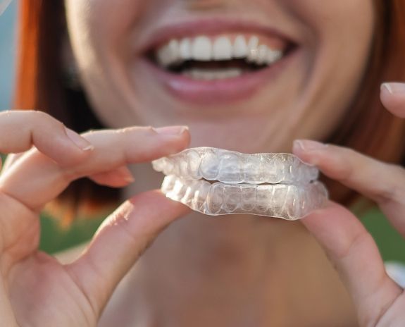Woman holding set of nightguards for bruxism