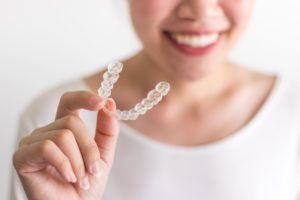 smiling person holding Invisalign in Cherry Hill 